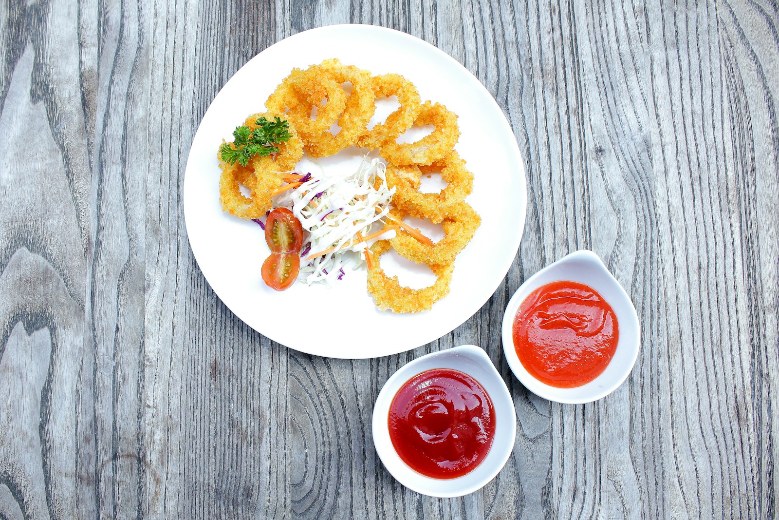 a white plate topped with onion rings and ketchup