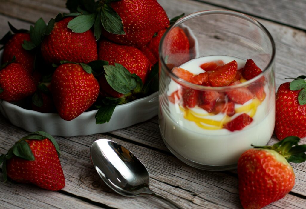 a bowl of fruit and a glass of milk with a spoon