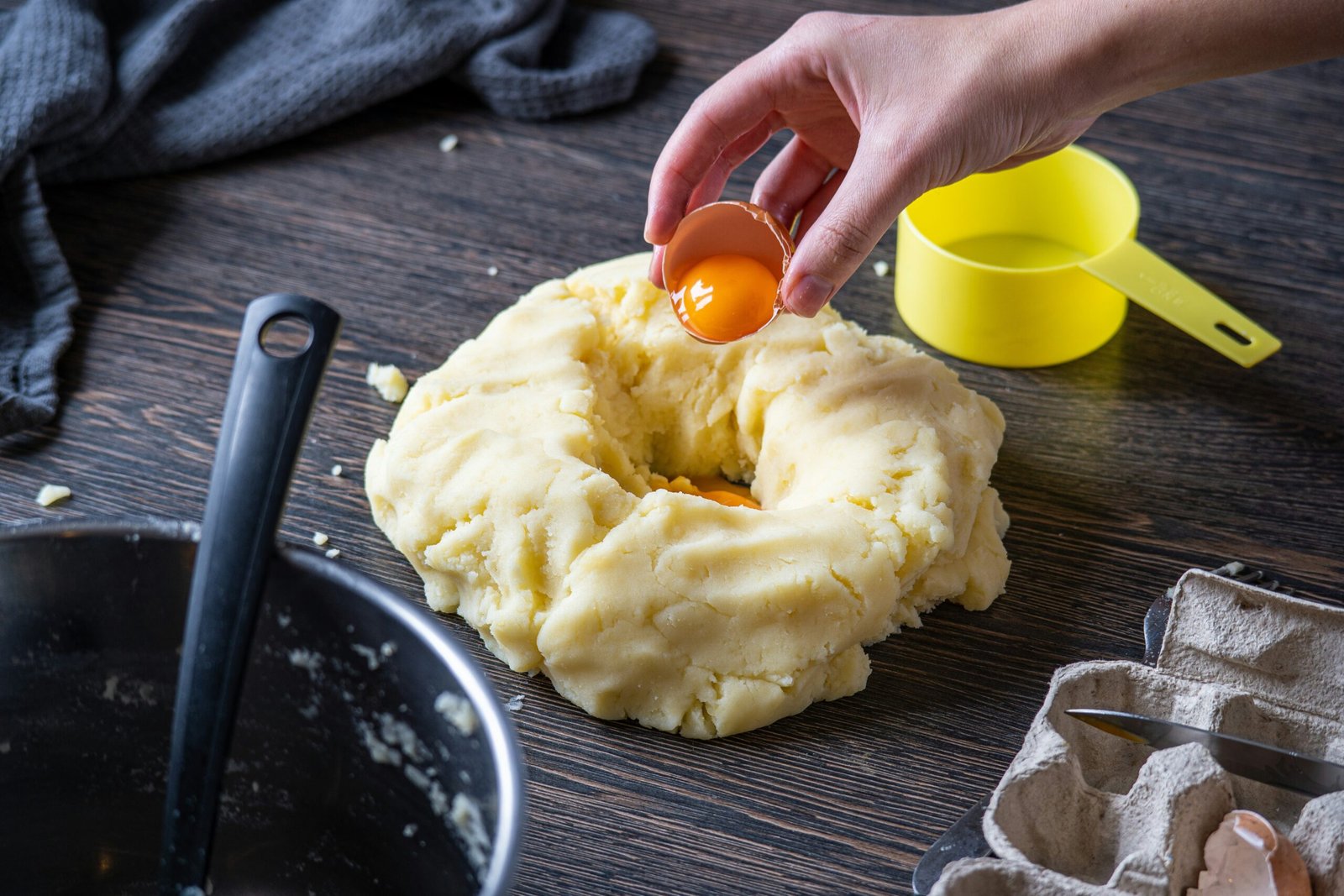 Person preparing dough with an egg yolk on a wooden surface, surrounded by baking tools, evoking the cozy, hands-on process behind easy and delicious baked butternut squash recipes.