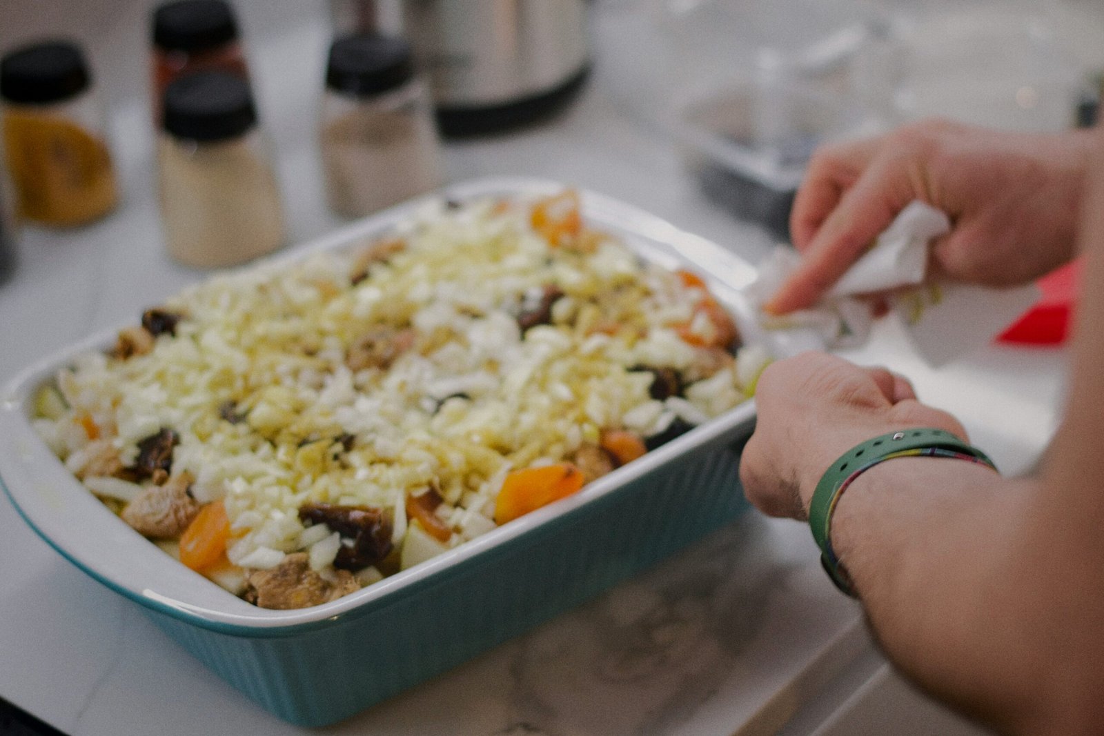 Colorful mix of chopped vegetables, meat, and cheese in a ceramic baking dish.