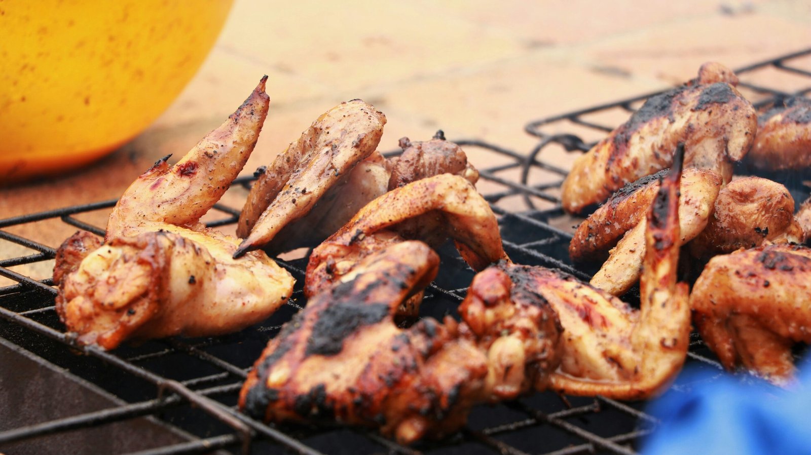 Grilled chicken wings with charred seasoning marks on a barbecue grill.