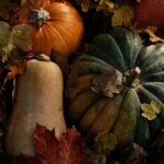 Assorted autumn frost squash and pumpkins surrounded by colorful fall leaves, showcasing seasonal produce for cozy fall recipes.