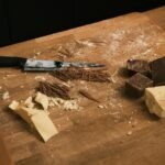 Chopped dark and white chocolate with shavings on a rustic wooden surface—ideal for crafting a healthy and tasty cottage cheese bark snack.