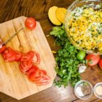 Fresh mango salsa being prepared with diced mangoes, tomatoes, jalapeños, and cilantro on a rustic wooden table, ideal for creative cooking recipes.