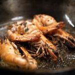 Golden-brown shrimp sautéed in a seasoned pan with herbs and spices, capturing the rich, savory essence of Pappadeaux’s Southern-style shrimp and grits.