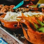 A colorful spread of ingredients inspired by the Bad Manners cookbook series, featuring shredded cabbage, vibrant sautéed vegetables, and seasoned plant-based protein served in rustic terracotta bowls, capturing the bold, no-nonsense flavor approach the brand is known for.