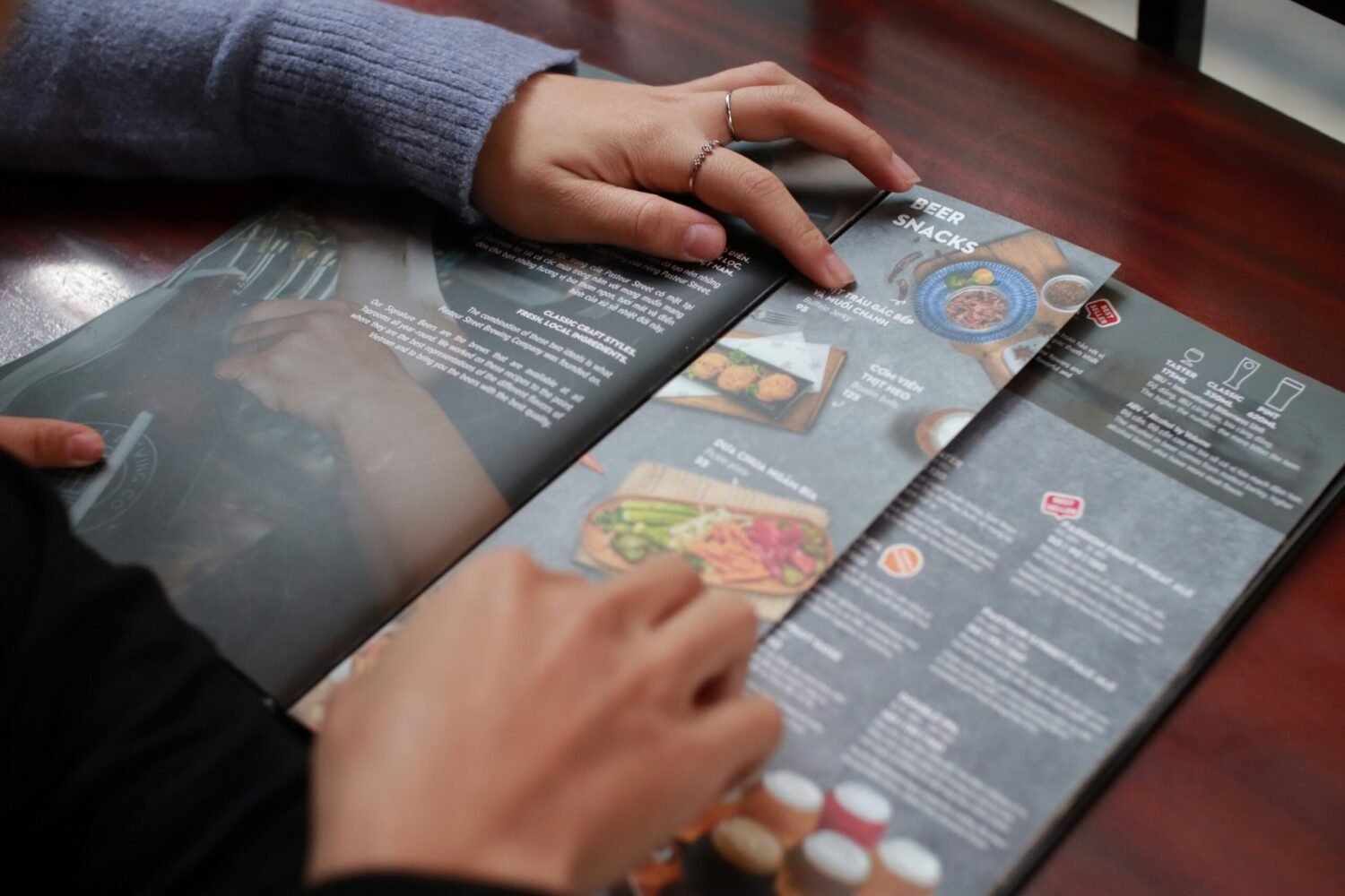 Hands flipping through a restaurant-style menu with photos and text, suggesting thoughtful layout and design choices for user interfaces.