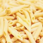 Close-up of uncooked penne pasta made from durum wheat semolina, illustrating pasta texture and shape for Italian recipe discussions.